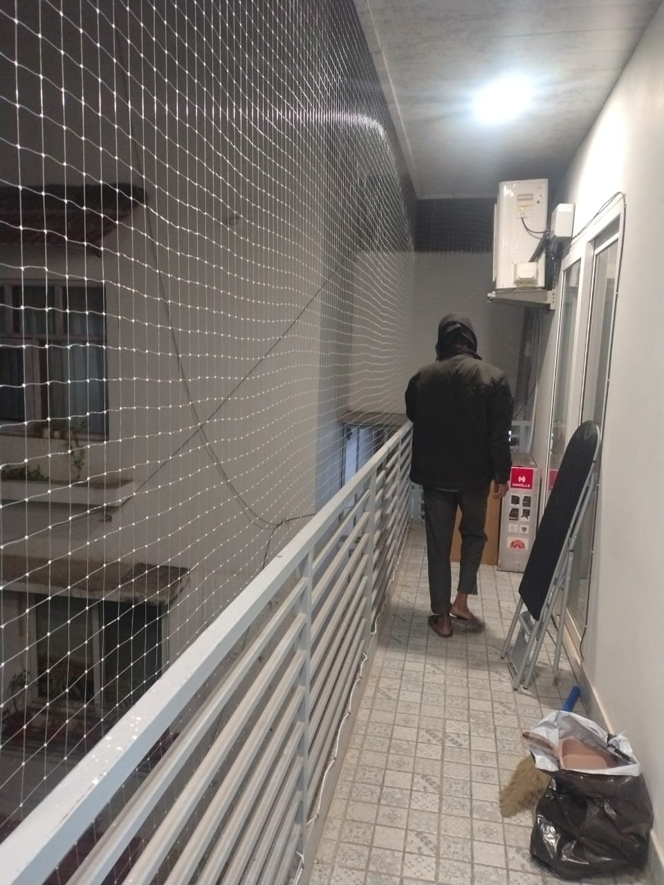 Installer fitting bird netting across a residential balcony opening